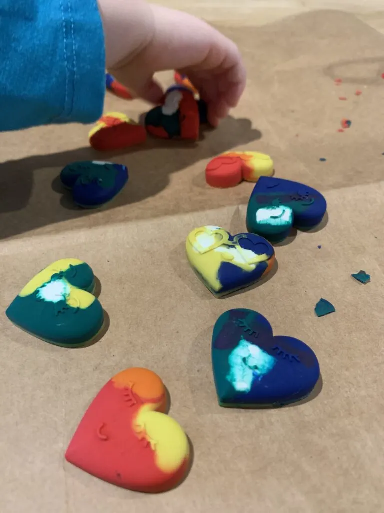 toddler hand picking up heart shaped crayons