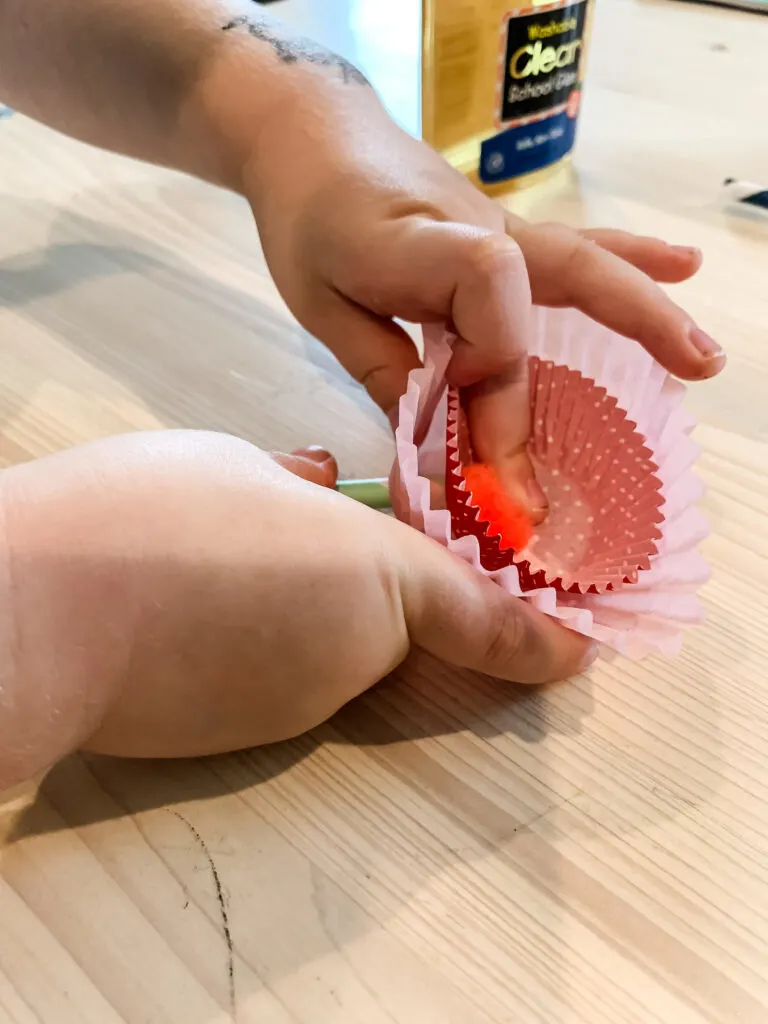 pressing a pom pom into a cupcake liner flower