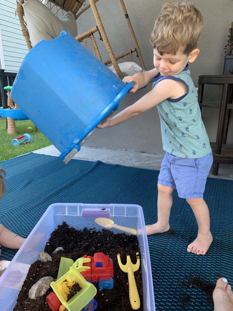 pouring water into a dirt sensory bin