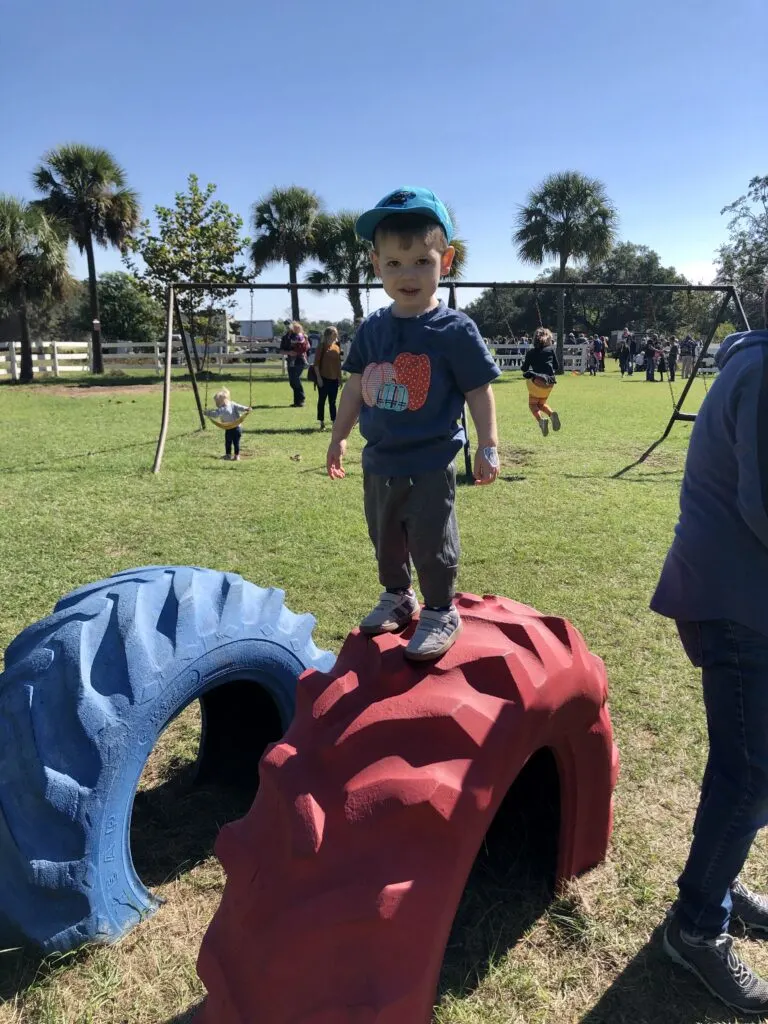 toddler on tractor wheel at pumpkin patch