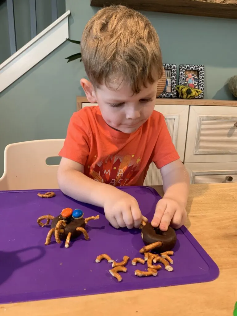 toddler making spider donuts for halloween