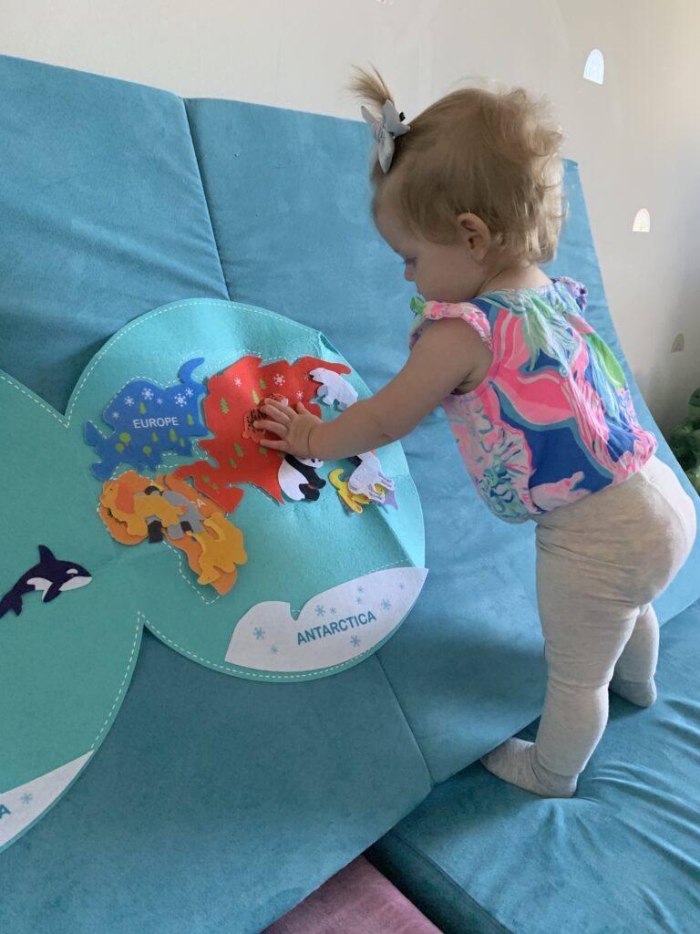 toddler sticking a felt map to a nugget comfort couch