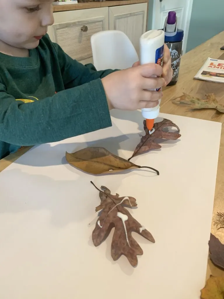 toddler gluing leaves to paper