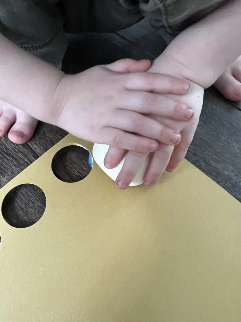 3 year old punching gold coins out of cardstock