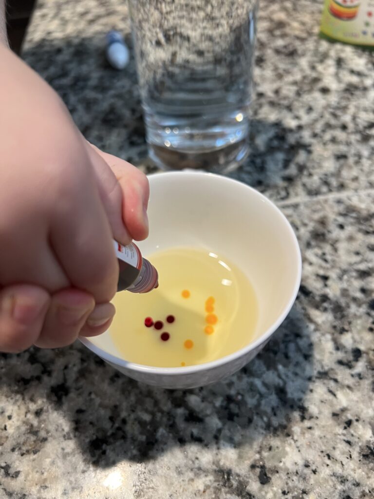 Putting food coloring into bowl of oil