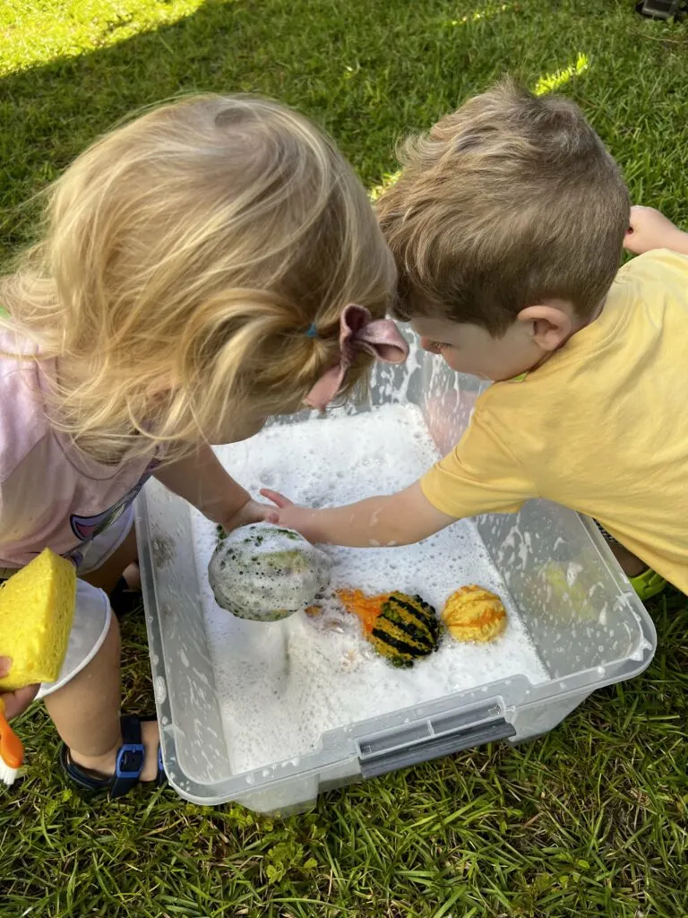 toddlers doing a pumpkin wash sensory bin