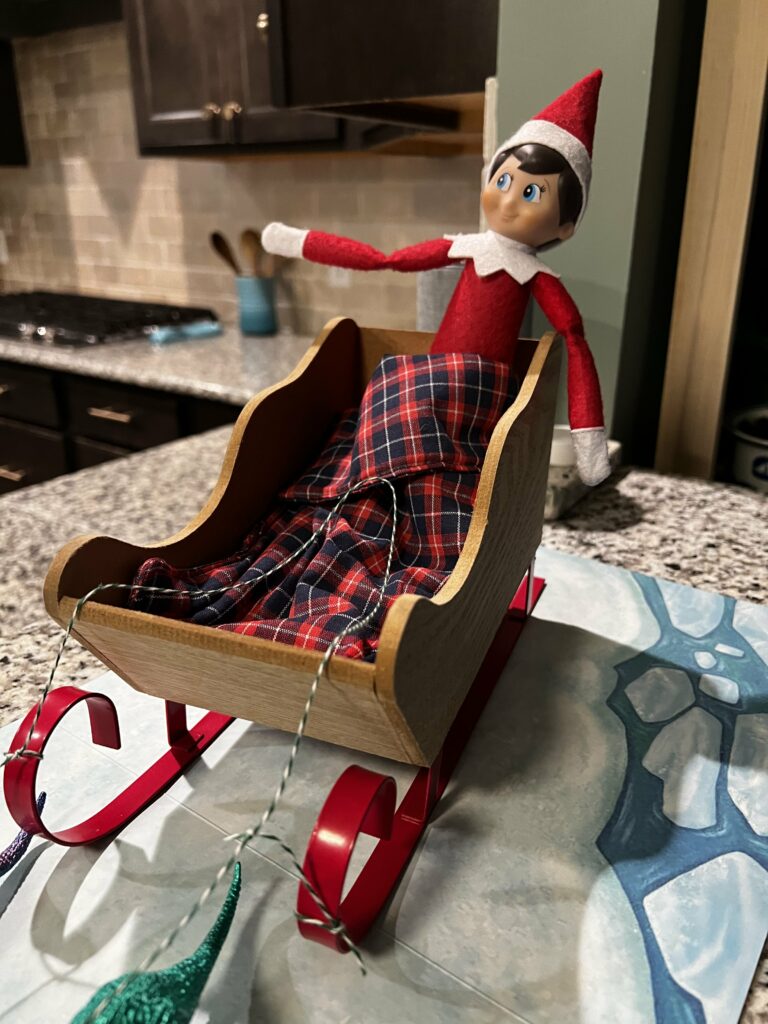 elf on the shelf in a small wooden sled