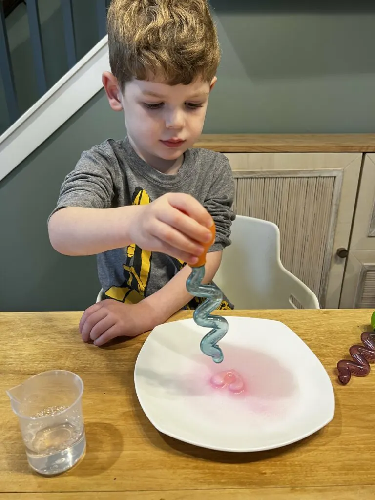 toddler dropping vinegar on baking soda hearts