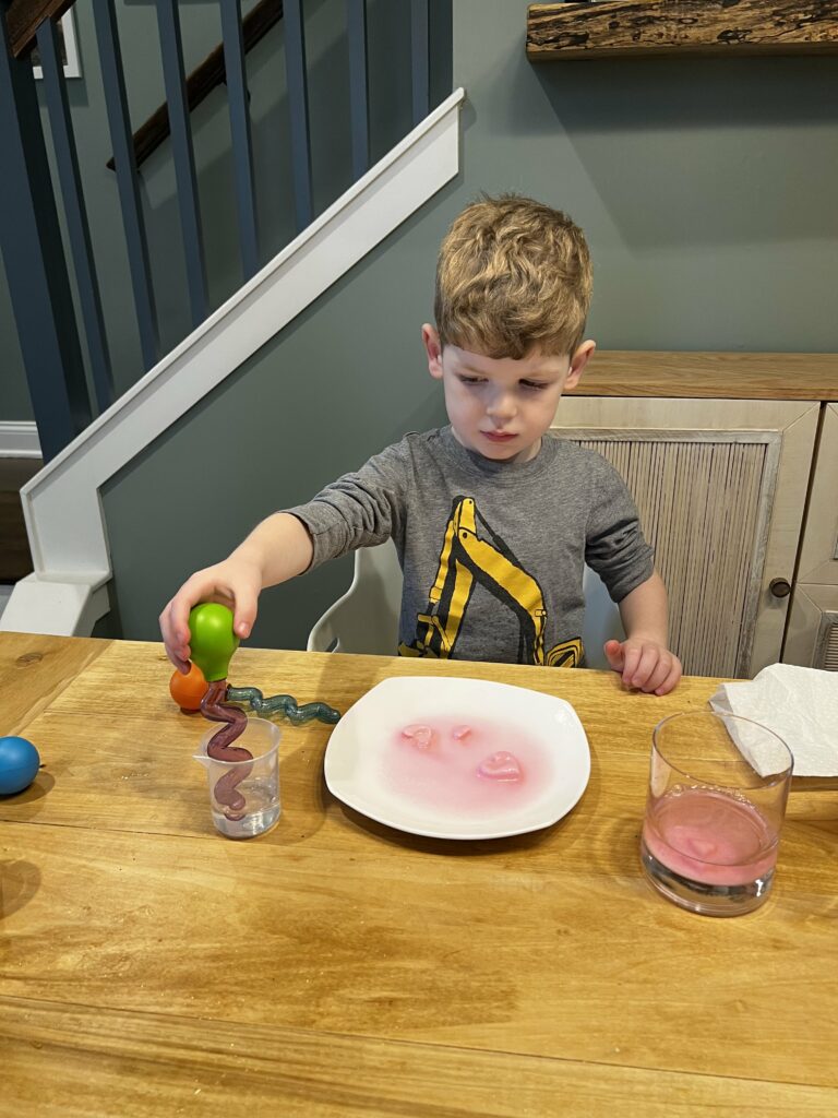 toddler dropping vinegar on baking soda hearts