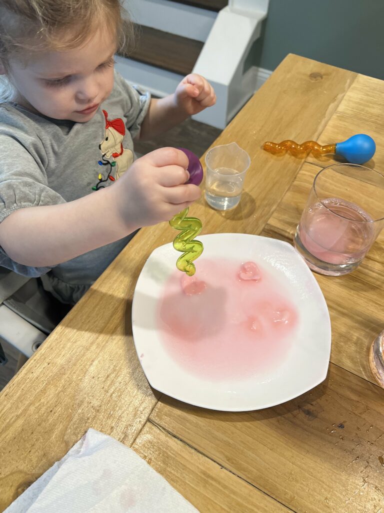 toddler dropping vinegar on baking soda hearts