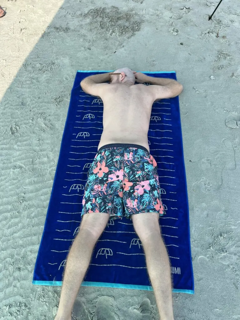 person laying on shibumi towel on the beach