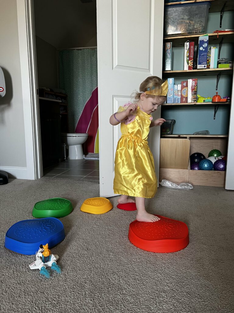 2 year old in dress up dress doing stepping stones