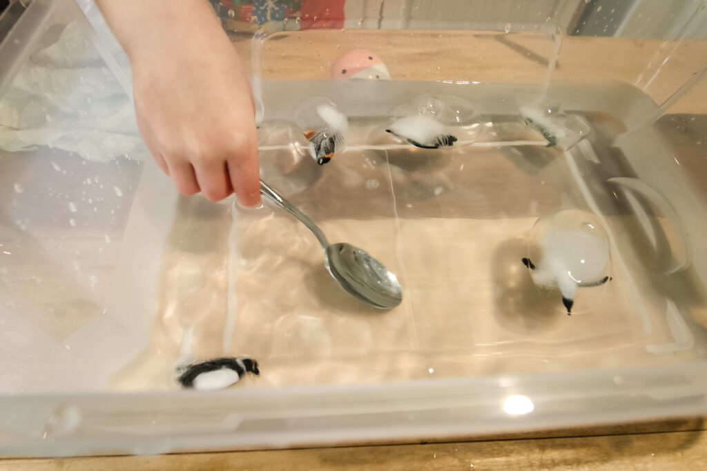 playing with frozen penguins ice sensory bin