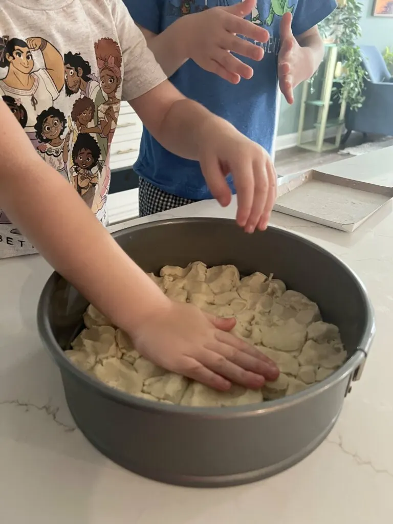 pressing sugar cookie dough to make a cookie cake