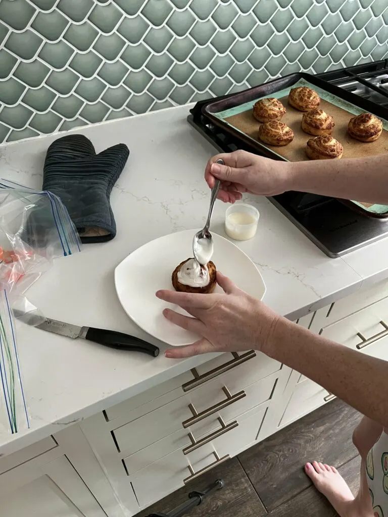 spreading icing on a cinnamon roll