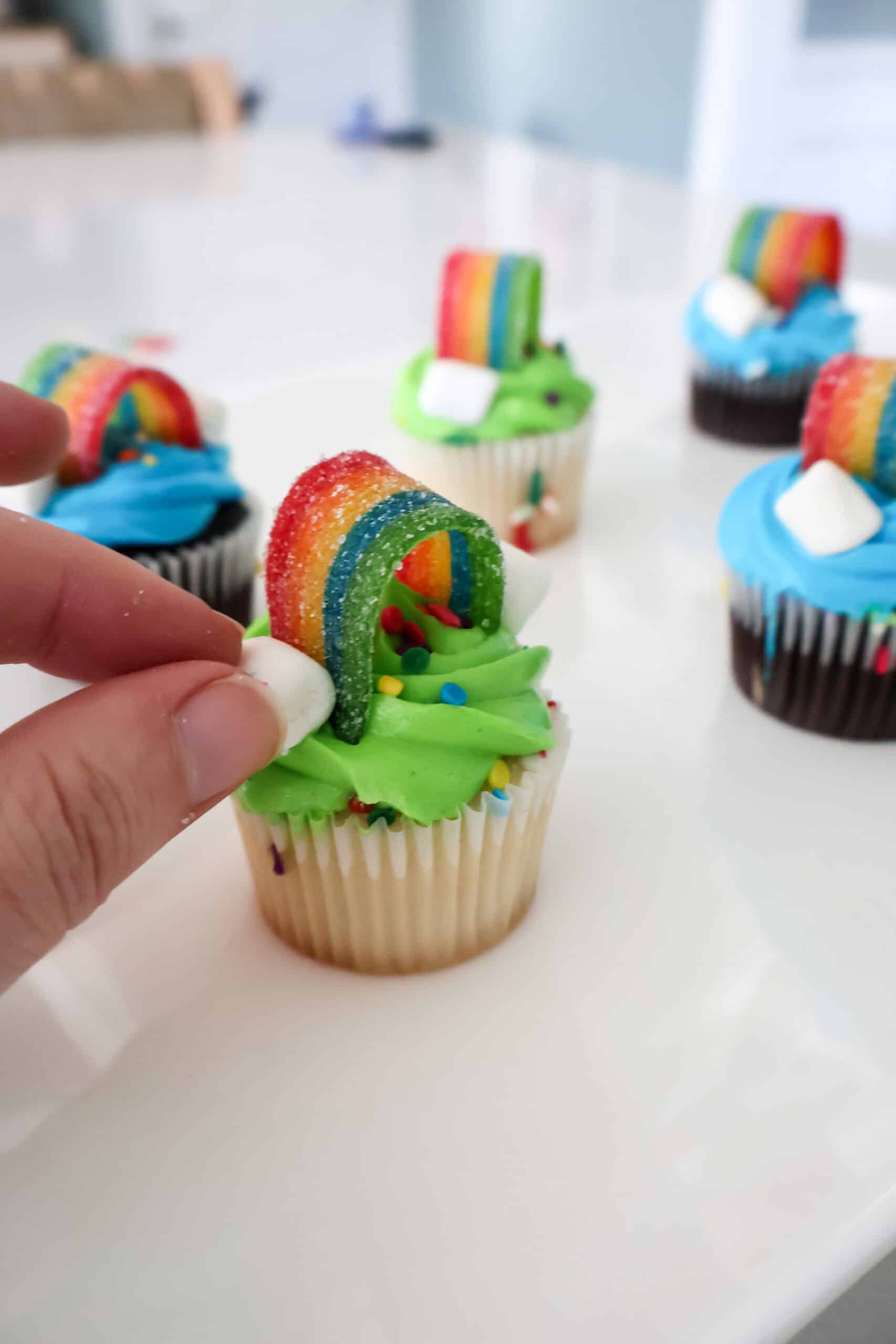 adding marshmallows to rainbow cupcakes