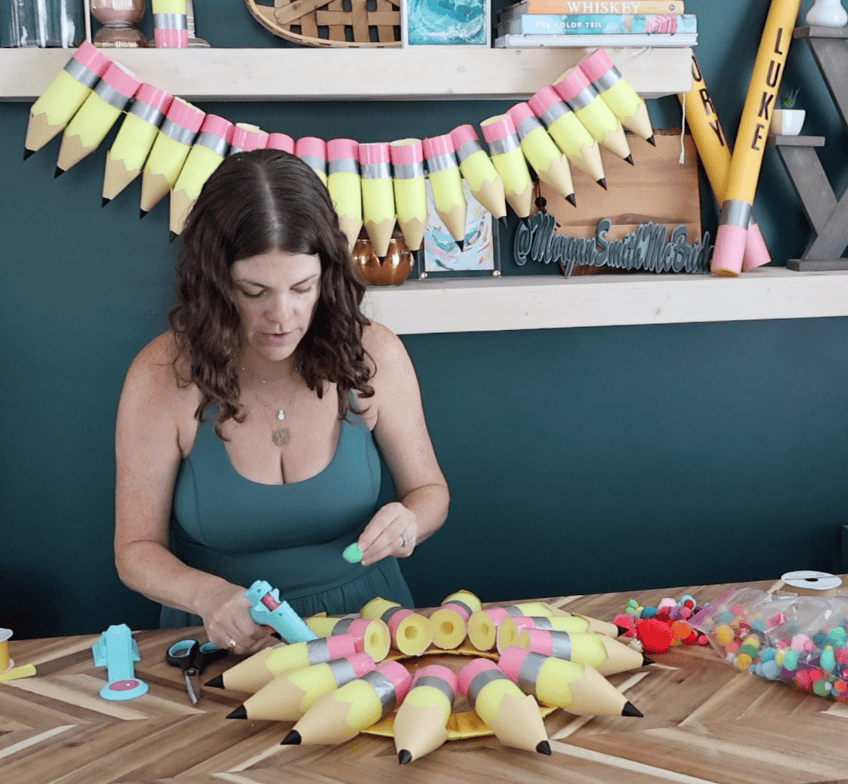adding pom poms to a pencil wreath