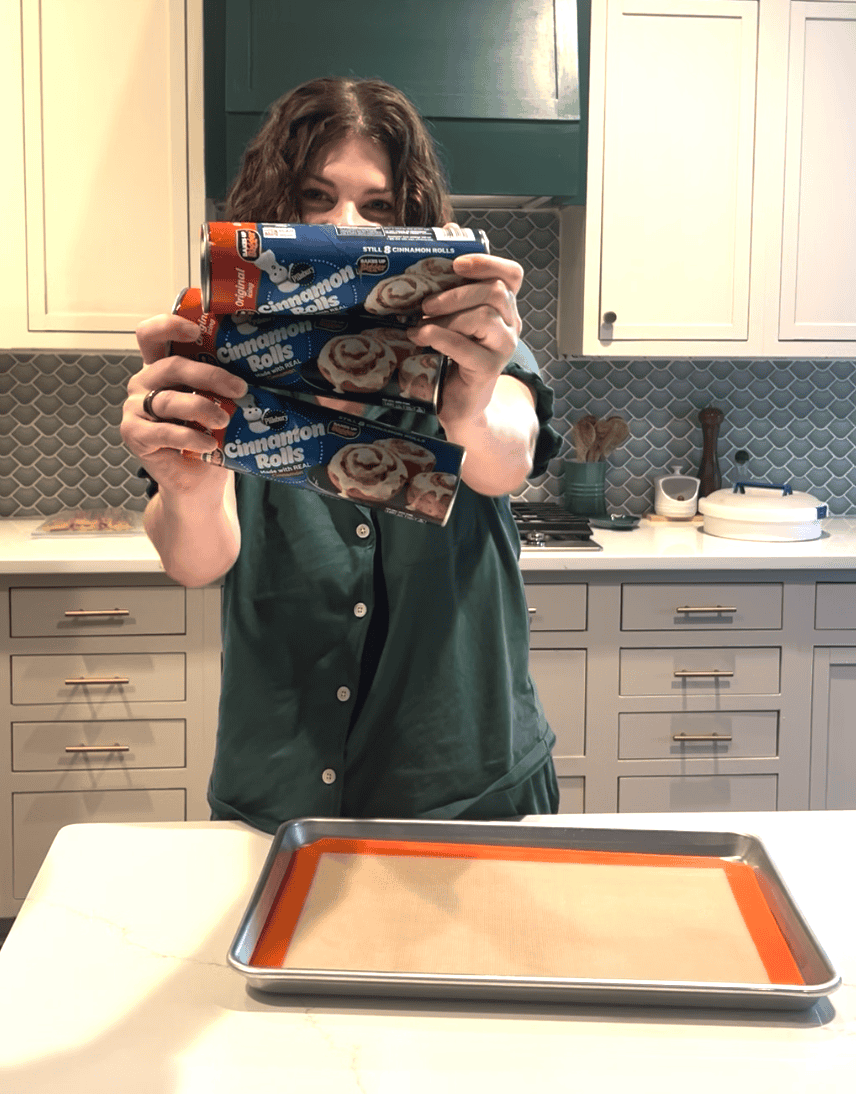 me holding up 3 cans of cinnamon roll dough