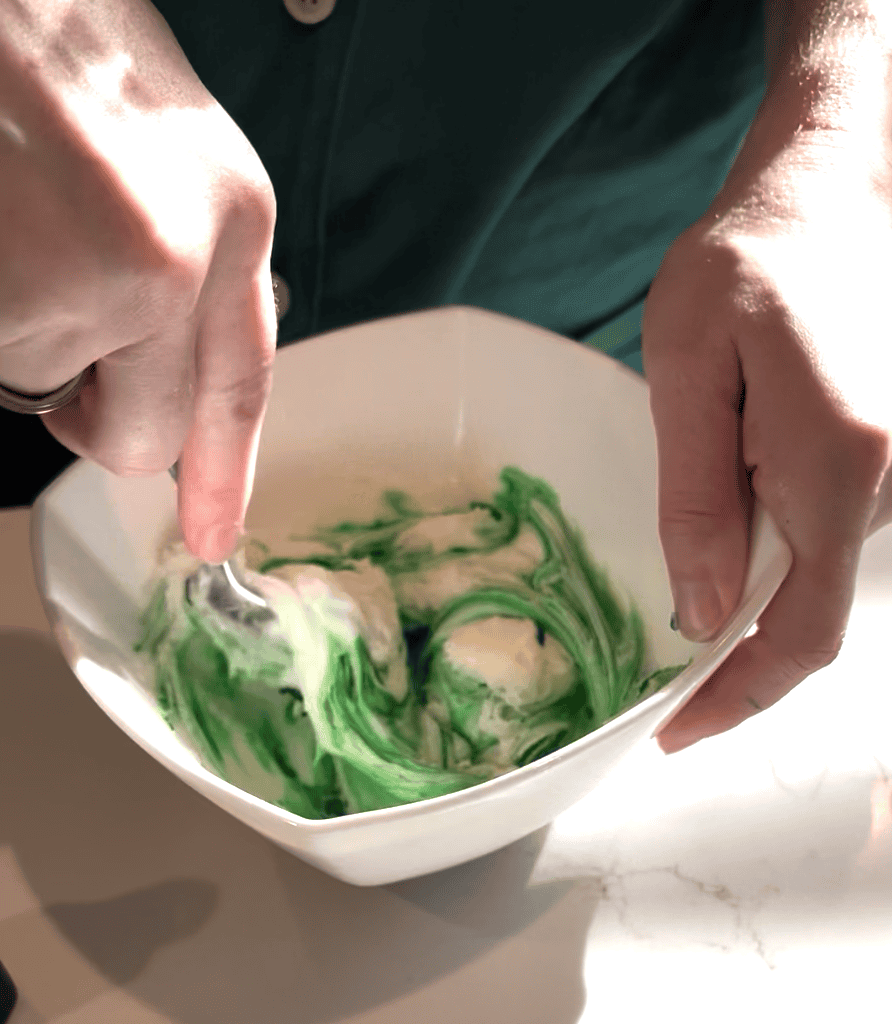 mixing green food coloring into icing
