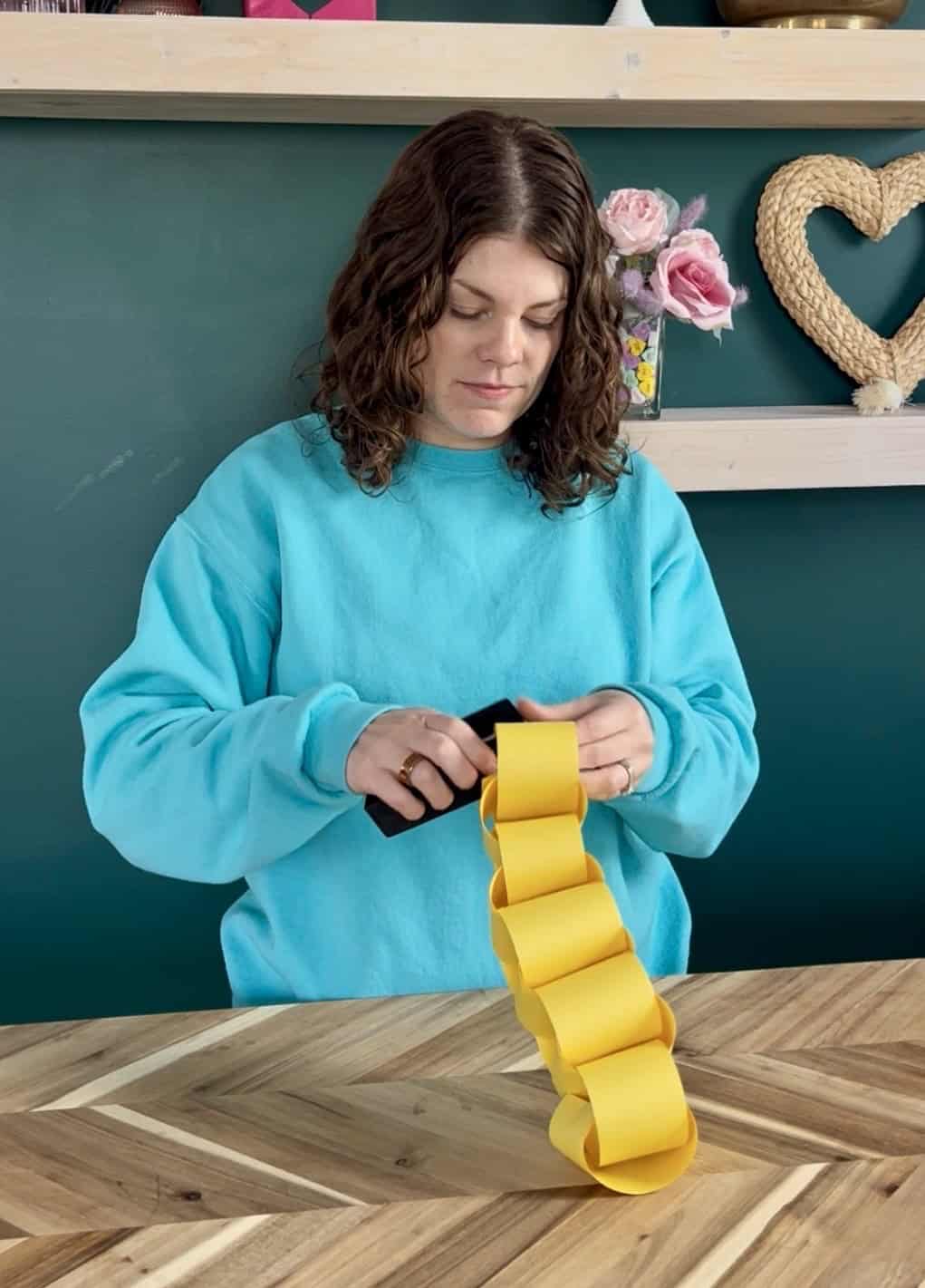 stapling yellow paper strips into a rapunzel paper chain