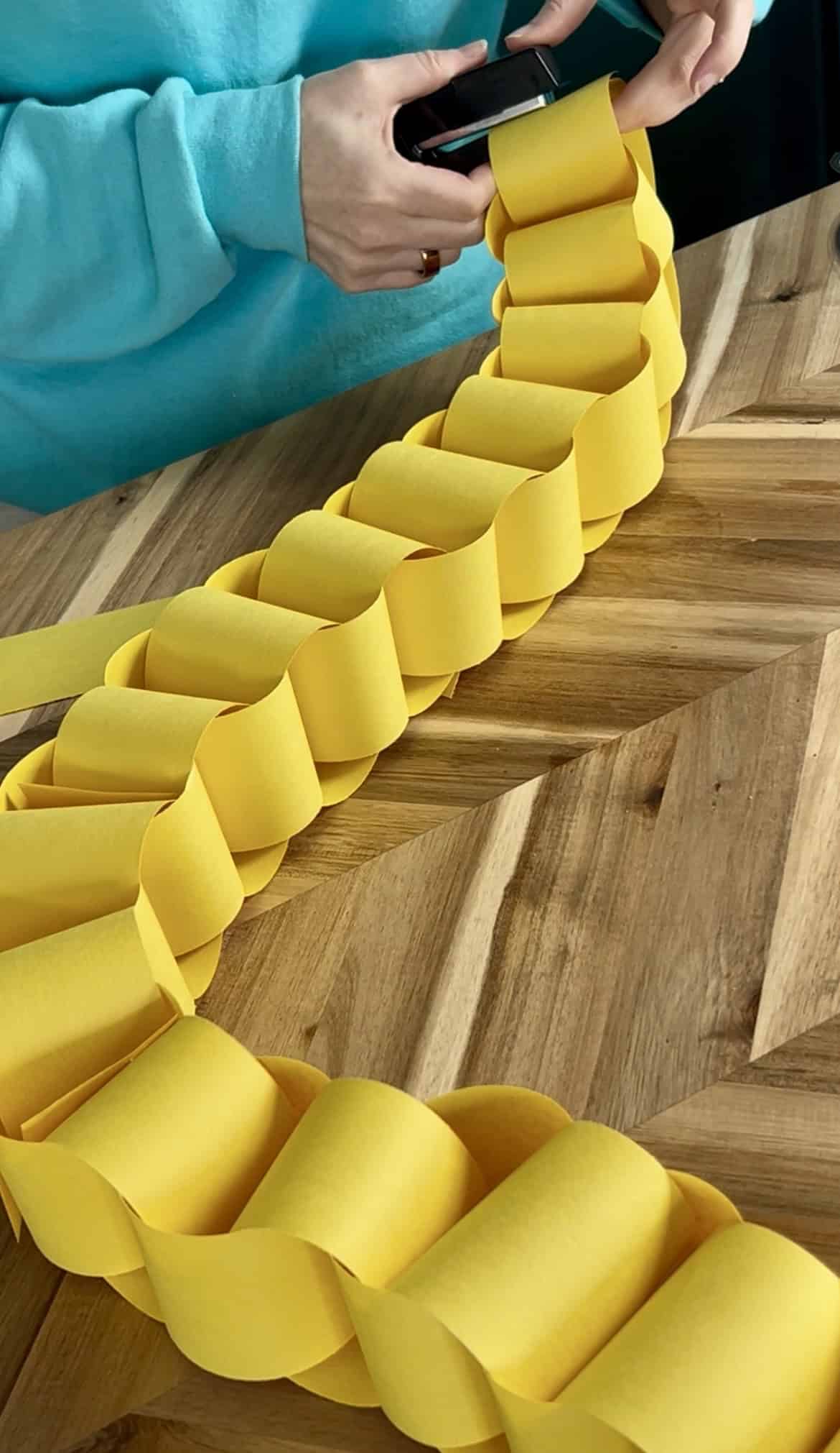 stapling yellow paper strips into a rapunzel paper chain